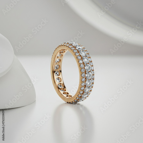 Close up of a gold eternity band ring with diamonds on a white surface background
