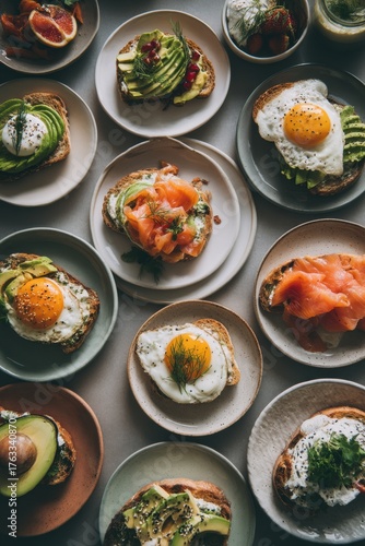 Overhead flat lay of gourmet toasts with avocado egg salmon grapefruit at brunch table setting