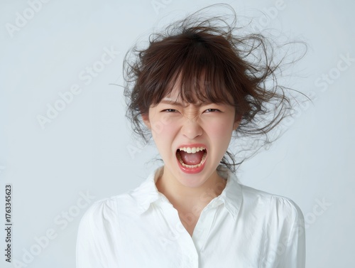 白いシャツを着た女性が怒りを爆発させて叫ぶ感情表現のポートレート写真