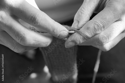 Knitting process of red fabric with needles, close-up of hands with yarn. Concept of hobby, creativity and coziness.
