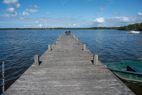 Wallpaper Mural An elderly couple sits side by side on a bench at Lac de Leon. They enjoy the calm waters and scenic beauty of the Landes region on a clear day. Torontodigital.ca
