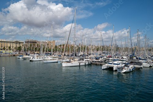 Scenic view of a marina filled with sailboats and yachts on a sunny day in a Mediterranean coastal city.