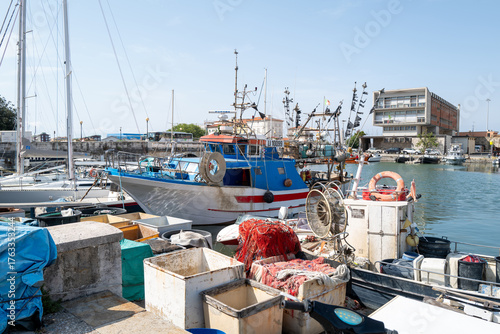 Traditional fishing boats docked at a small harbor on a sunny day.