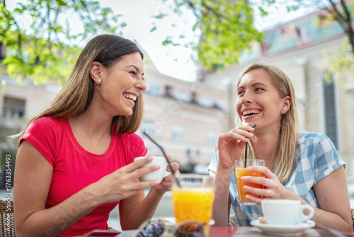 Two smiling women enjoying coffee and juice in the cafe