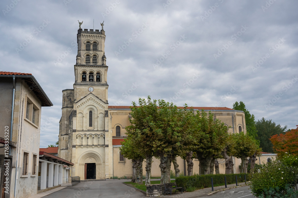 Fototapeta premium Explore the stunning architecture of the Basilica of Notre-Dame-de-Buglose, located in Saint-Vincent-de-Paul, Landes. The building showcases intricate designs against a moody sky.