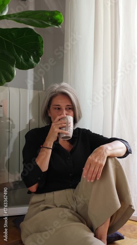 Serene mature woman savoring a hot drink in a cozy home setting