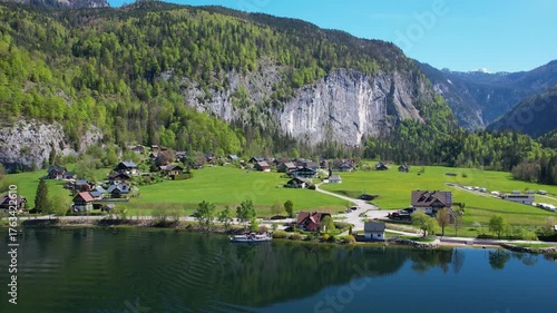Experience the breathtaking aerial views of Grundlsee Lake in Austria, highlighting the serene waters, green landscapes, and majestic mountains during a clear day.