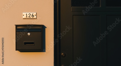 mailbox with house number on beige wall bathed in warm sunlight, symbolizing daily deliveries