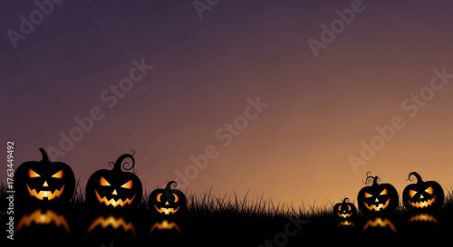 Silhouette of several glowing jack-o'-lanterns on dark grass against a gradient sky, symbolic of Halloween celebration and spooky atmosphere