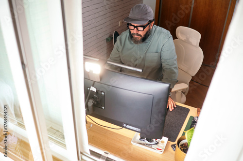 Man standing at desk working on computer.