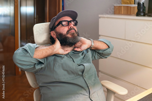 Man leaning back in chair massaging his neck