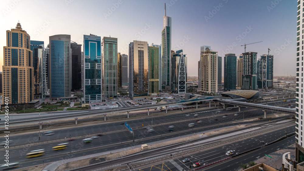Fototapeta premium Aerial view of Jumeirah lakes towers skyscrapers night to day timelapse with traffic on sheikh zayed road.