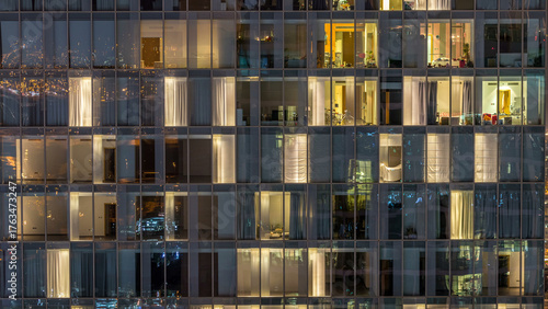 Windows of the multi-storey building of glass and steel lighting inside and m...
