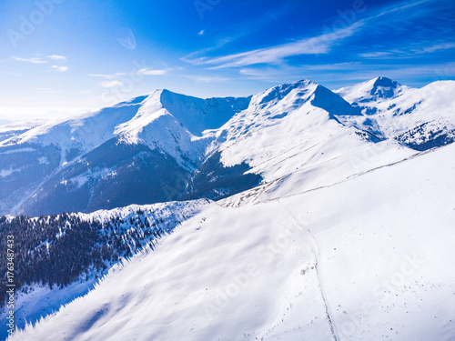 Winter landscape in the Carpathian Mountains, Romania. Snow-covered peaks, frozen forests, and a peaceful mountain valley bathed in soft morning light.