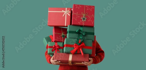 Woman holding stack of different Christmas gifts on green background