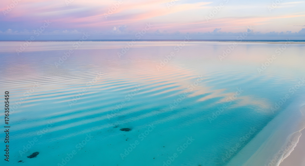 Fototapeta premium Vibrant pastel sky reflected on the serene turquoise tropical ocean, with gentle ripples on the calm water at sunrise or sunset, creating a peaceful paradise scene