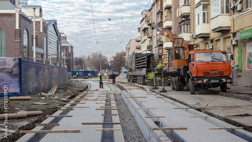 Foto Tram rails at the stage of their unloading from truck by crane on concrete plates on the road timelapse