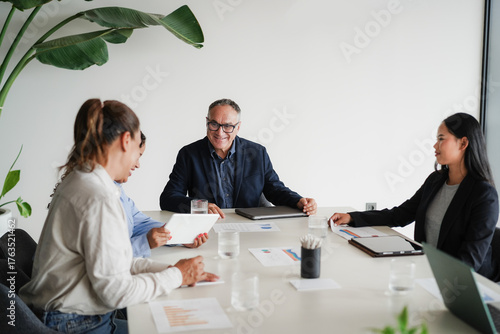 Multigenerational business people sharing ideas inside company office - Multiracial colleagues discussing new financial project - Brainstorming and corporate concept - Main focus on center man face
