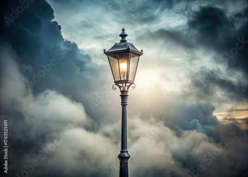 Antique black street lamp standing alone under a cloudy sky with soft white fog