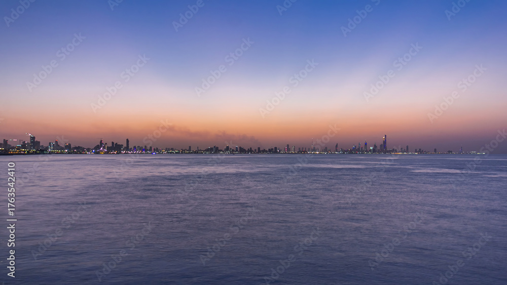 Obraz premium Skyline with Skyscrapers day to night timelapse in Kuwait City downtown illuminated at dusk. Kuwait City, Middle East