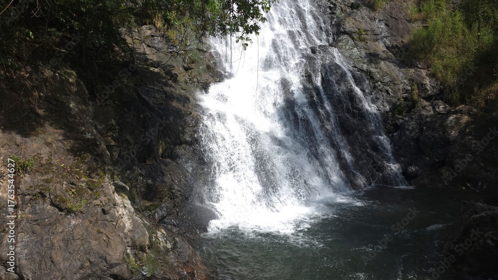 Fototapeta premium Majestic Waterfall Cascading Over Rocky Cliff Surrounded by Lush Greenery in Nature