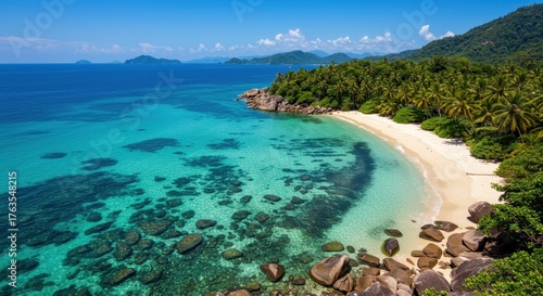 Idyllic tropical white sand beach bordering crystal clear turquoise ocean water and lush palm jungle