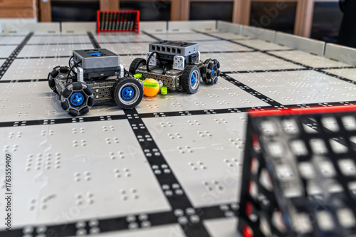 Small robots compete in a technology display at a robotics event in a classroom setting