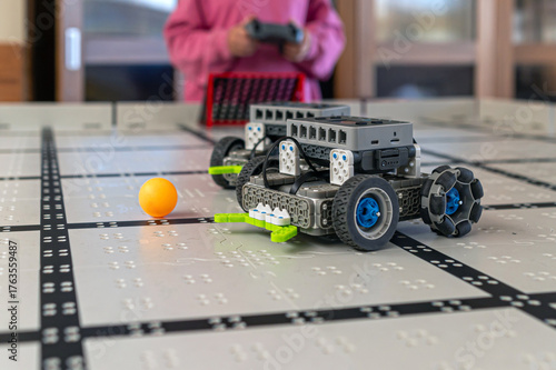Robot car designed for play interacts with a ball on a grid surface