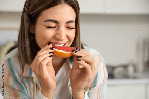 Young woman eating grapefru...