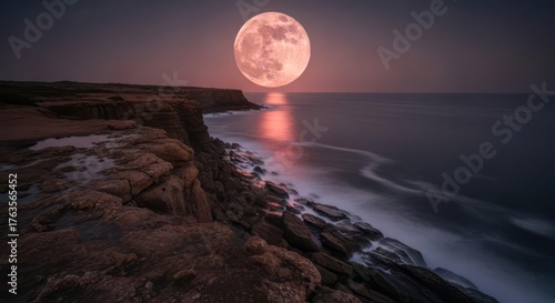 Dramatic full moon rising over a rugged ocean coastline with waves crashing, reflecting on the water at night.