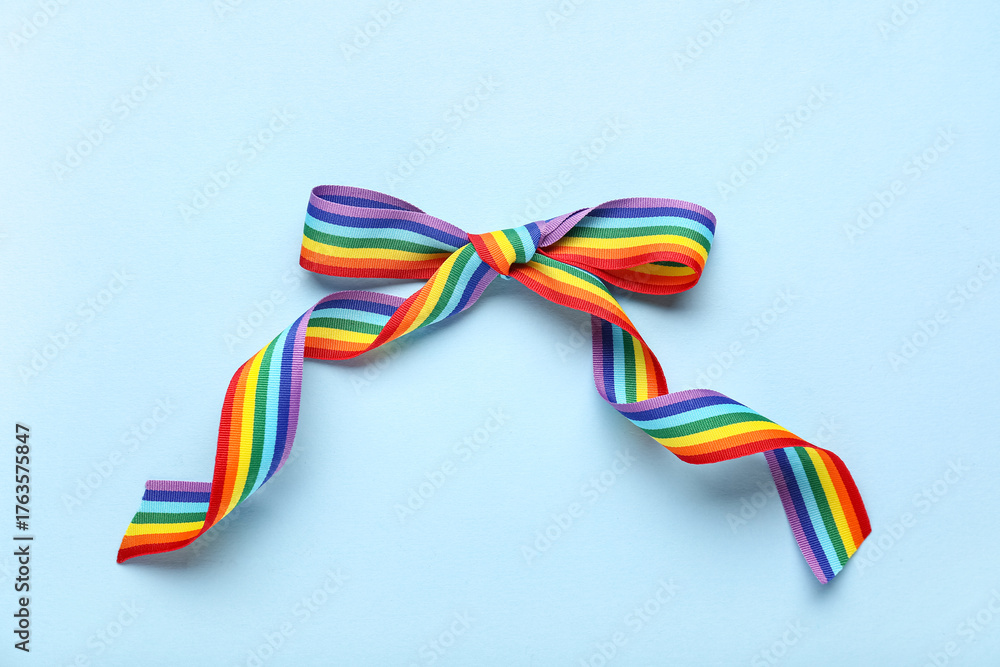 Fototapeta premium Bow made of rainbow ribbon on blue background. LGBT concept