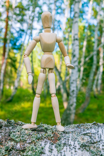 vertical photo of a wooden doll on the background of a summer forest