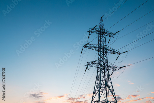 silhouette of a single pole of high-voltage electricity transmission lines against the blue sky at dawn