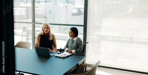 Two women discussing a project in a modern office setting