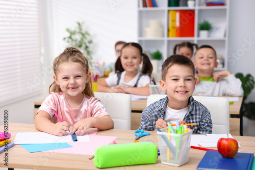 Photos Happy children at wooden desks during art lesson in elementary school