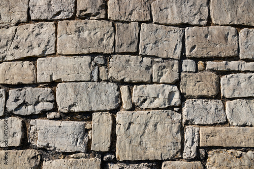 background, stone wall structure, constructed from light-colored stones of varying sizes, with some stones featuring darker veins or inclusions