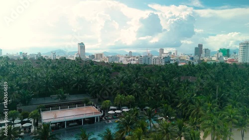 Wallpaper Mural Da nang cityscape showcasing a vibrant blend of urban development and tropical nature, with a dense canopy of palm trees leading up to diverse architecture and a mountain backdrop Torontodigital.ca