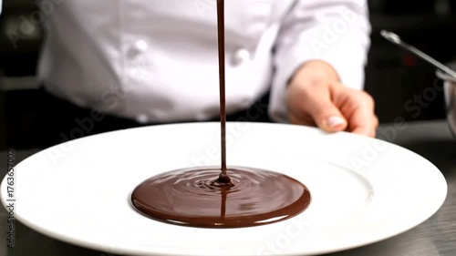 Chef elegantly pouring rich chocolate ganache onto a pristine white plate in a modern kitchen