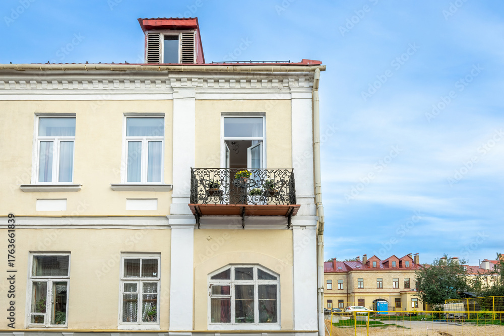 Obraz premium Old Yellow Building with Decorative Balcony and Blue Sky