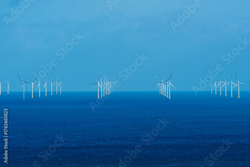 Rows of offshore wind turbines rising from deep blue water