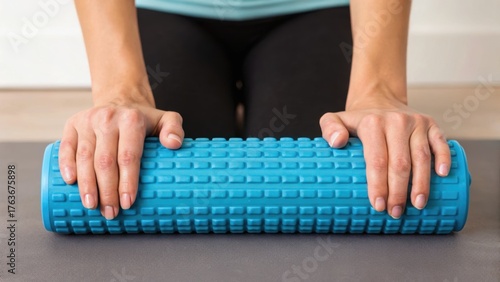 A person uses a blue foam roller on a yoga mat, demonstrating a self-massage technique for muscle relief and relaxation.