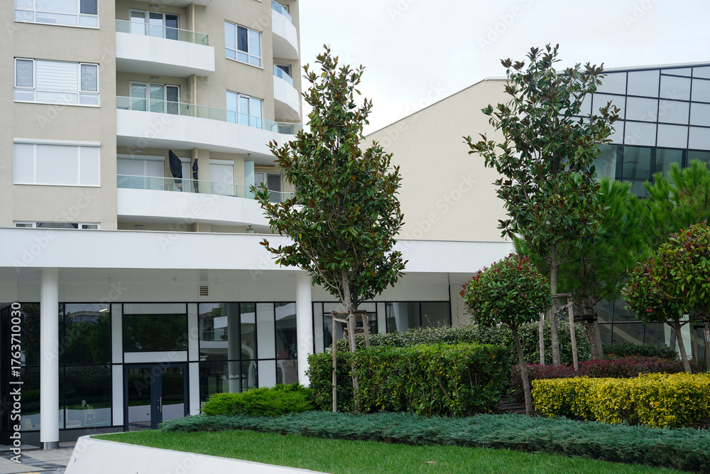 Fototapeta premium A modern residential building with landscaped greenery and well-maintained trees in front