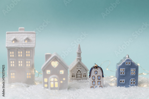 Miniature ceramic houses with festive illuminations for Christmas decoration. Concept for winter holidays and a seasonal atmosphere. Christmas background, greeting card.