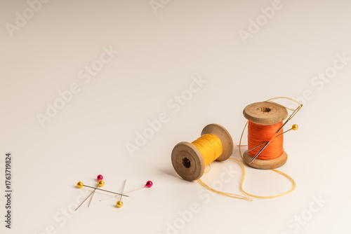 Spools of thread and sewing needle on plain background symbolize craftsmanship and artistic creation.Сoncept of handmade, craft and artistic expression.