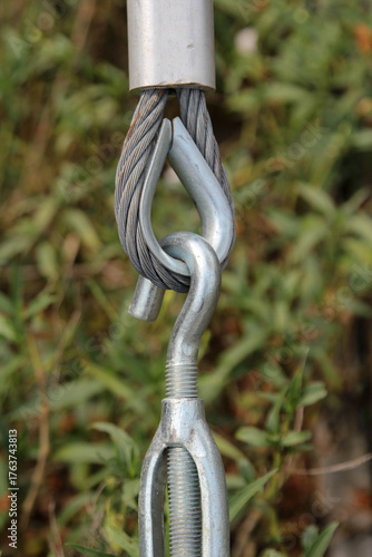 Closeup of metal fasteners and steel wire rope on natural background blur.