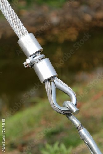 Closeup of metal fasteners and steel wire rope on natural background blur.