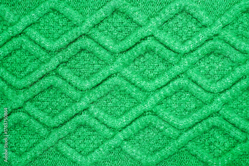 Vibrant green knitted fabric texture with traditional cable knit diamond pattern. 