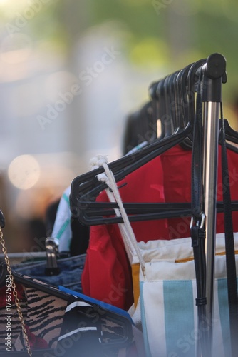 Feira de Roupas de Segunda Mão ao Ar Livre com Cabides Negros e Roupas Coloridas Penduradas em Arara, Fundo Desfocado