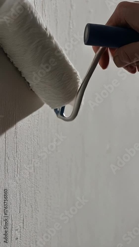 Painting a wall with a paint roller, close-up view of the process