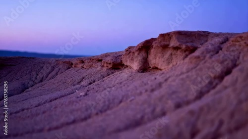 Desert landscape at twilight with purple and blue sky and textured sandy hills